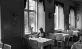 Svartå Herrgård 28 juli 1966

I matsalen på Svartå Herrgård sitter en kvinna i ljus, ärmlös sommarklänning vid ett bord. Matsalen är fylld med bord och stolar. En väggklocka samt lampor sitter på väggarna.