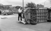 Krock, 26 juni 1967

En polis står invid en omkullvält, vit buss som varit med om en krock. En svart bil som också krockat står i bakgrunden med framhjulen uppe på trottoaren. Folk står runtomkring och betraktar olycksplatsen.