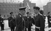 Kungen I3 28 augusti 1967

Kung Gustav VI Adolf besöker Örebro Livregementes Grenadjärer i Grenadjärsstaden. Han står mittemot en militär som hälsar honom med en höjd sabel i sin högra hand. Båda är klädda i militäruniform. En massa militärer syns bakom de båda nyss nämnda herrarna. En av dem bär en befälsbricka om halsen.