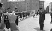 Kungen I3 28 augusti 1967

Kung Gustav VI Adolf besöker Örebro Livregementes Grenadjärer i Grenadjärsstaden. Han passerar förbi en rad uppställda militärer på linje och som skyldrar gevär. Han gör honnör mot dem. En militär med en fana och befälsbricka om halsen syns till vänster. En fotograf tar bilder med en kamera i förgrunden.