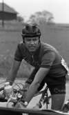 Orubricerad 18 maj 1967

Närbild på en tävlingscyklist. Han är klädd i idrottskläder med kort T-shirt och shorts samt med hjälm på huvudet. Han har ett armbandsur på vänster handled samt en vattenflaska som sitter fast i en metallställning fram på cykeln.