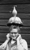 Orubricerad 21 augusti 1967

Närbild på en leende kvinna som befinner sig i Wadköping i Örebro. Hon är klädd i en lustig hatt. Hon bär glasögon och är klädd i en ljus blus och en ljus kappa.
