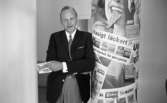 Orubricerad 21 augusti 1967

Direktören står vid en reklampelare på Örebro Kexfabrik. Han är klädd i mörk kavaj, ljusa byxor, vit skjorta och mörk slips. Han håller ett paket apelsinkex i sin högra hand. På reklampelaren står 