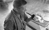 Kembels slutar, Blå stjärnan, 8 juli 1967

En man sitter i en matsal invid ett bord med en bricka fylld med tallrikar, bestick glas och en uppläggningsskål i metall. Han håller en pipa i sin vänstra hand. Han är klädd i en kort T-tröja. Mannen skrattar.