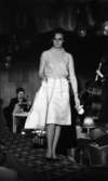Korsettuppvisning 26 april 1965

Kvinnlig modell med ärmlös blus, kjol och en jacka i handen.
Firma Härold, Hagenfeldts personalvisning på Frimis.
