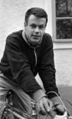 Palle Munther 18 maj 1967

Närbild på en ung man som är klädd i svart sportjacka med ljusa kanter, rutig skjorta och grå byxor och som sitter på en sportcykel.