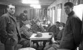 Manöver i Kilsbergen 1 21 februari 1967

En grupp soldater sitter vid bord i en sal i en byggnad i Kilsbergen. Tre stycken står upp. Alla är klädda i militäruniformer. En av de sittande soldaterna röker en cigarrett.