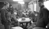 Manöver i Kilsbergen 1 21 februari 1967

En grupp soldater sitter vid bord i en sal i en byggnad i Kilsbergen. Tre stycken står upp. Alla är klädda i militäruniformer. En av de sittande soldaterna röker en cigarrett.