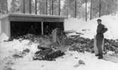 Manöver i Kilsbergen 21 februari 1967

Fyra militärer befinner sig i Kilsbergen i och i närheten av en vedbod. Tre av dem sitter inne i vedboden och den fjärde står på den snötäckta marken invid en såg. Alla bär miltäruniformer.