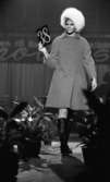 Miss Backfisch 9 oktober 1967

En modell går på catwalken klädd i en ljus kappa med en vit pälsmössa till. På fötterna har hon svarta stövlar. I sin högra hand håller hon en skylt med siffran 38 på.