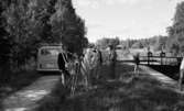 Hjälmaren filmas 19 juli 1967

Fotograf med medarbetare. Två män står och pratar
med varandra. En man sköter slussen och en flicka ser på. Bil parkerad i bakgrunden.