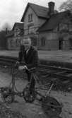 Orubricerat 16 maj 1968
Nedlagd järnvägsstation.
Mannen hänger över en cykeldressin av Fjugesta maskinfabriks tillverkning. Stationshuset i bakgrunden finns längs järnvägssträckan Frövi-Krylbo och kan vara Sällinge station.