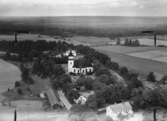 Flygfoto över Götlunda, kyrkan, bostadshus och byggnader.
Bilden tagen för vykort.
Förlag: A.B. Bröderna Björn, Götlunda.