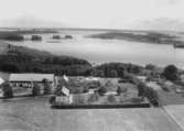 Flygfoto över Hjälmarsholm, bostadshus och ekonomibyggnader.