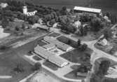 Flygfoto över Götlunda, kyrkan och bostadshus.
Bilden tagen för vykort.