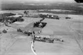 Flygfoto över Ervalla, kyrkan, bostadshus och ekonomibyggnader.
Bilden tagen för vykort.
Förlag: F. L. Carlsson, Ervalla.