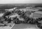 Flygfoto över Snavlunda, kyrkan, bostadshus och byggnader.
Bilden tagen för vykort.