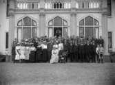 Ett stort gruppfoto vid Boo slott. Längst fram sitter Hugo Hamilton med blombukett, bredvid hustrun Ebba Hamilton (född von Essen). Bakom dem står sönerna Carl Hamilton och Hugo Hamilton, med sina fruar Märta Hamilton, respektive Greta Hamilton (född Ribbing).