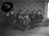 Rumsinteriör, grupp sex män vid bordet.