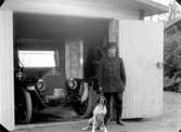 En man och en hund i garagedörren, en bil i garaget. 
Bilen är en 1912 års Overland som hade reg.nr. A1695. Den registrerades den 29:e juni 1912 och ägdes av disponent Ade Andersson, Hjortkvarn.