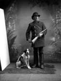 En man med gevär och en hund.
