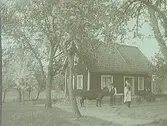 12 maj 1934. Man, kvinna och en ko framför ett hus.