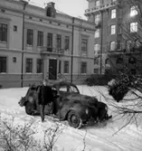 Fo-staben, bilarna.
En man vid bilen, byggnader i bakgrunden.