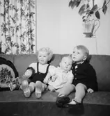 Rumsinteriör, tre barn i soffan.
Rulle Molin