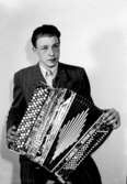 En man med musikinstrument (dragspel).
Troligen Sten Olov Årling (1926-2000).