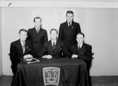 Rumsinteriör, fem unga män vid ett bord.
Karlslunds S.D.U.K.