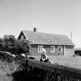 En pojke.Envånings bostadshus i bakgrunden.