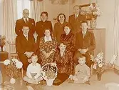 Rumsinteriör, familjegrupp 11 personer.
Fam. Andersson med blommor, högtid.
