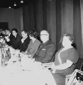 Rumsinteriör, grupp vid bordet. Personalklubben uppvaktar, Majgren avtackas.
Örebro Kexfabrik.