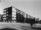 Bostadshus i fem våningar med affärer i gatuplanet.
John Andersson, Byggnadsfirma, Järnvägsgatan 11-13.