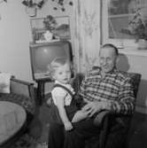 Rumsinteriör, en man och ett litet barn.Fru Britta Jönsson (beställare ?).