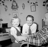 Rumsinteriör, en man och två barn.Fru Britta Jönsson (beställare ?).