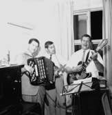 Interiör, orkester, tre män med musikinstrument.
Lindmans 50-årsdag.