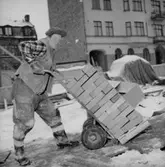 Byggnadsarbete, en man.
Oscaria (beställare ?).
Tegelkörare. 
Kvarteret Tunnbindaren. Huset i bakgrunden med port är hörnhuset Näbbtorgsgatan- Änggatan.