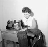 Interiör, en kvinna vid symaskinen.

