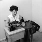 Interiör, en kvinna vid symaskinen.

