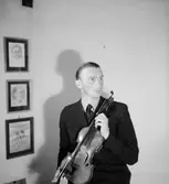 Rumsinteriör, en man med musikinstrument (fiol).
Storå