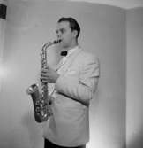 En man med musikinstrument (saxofon).
Helgesson, Astoria orkester.