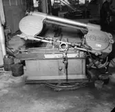 Verkstadsinteriör, järnsåg, en man.
Gustafsson & Görtz