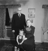 Rumsinteriör, familjegrupp tre personer.
Fru Alms födelsedag.