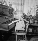 Rumsinteriör, en liten flicka vid pianot.