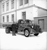 Fo-staben, bilarna.
En man vid bilen, byggnader i bakgrunden.