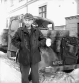 Fo-staben, bilarna.
En man vid bilen, byggnader i bakgrunden.