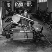 Verkstadsinteriör, en man vid järnsågen.
Gustafsson & Görtz