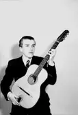 En man med musikinstrument (gitarr).
Axel Bellman