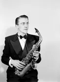 En man med musikinstrument (saxofon).
Olle Wahlström